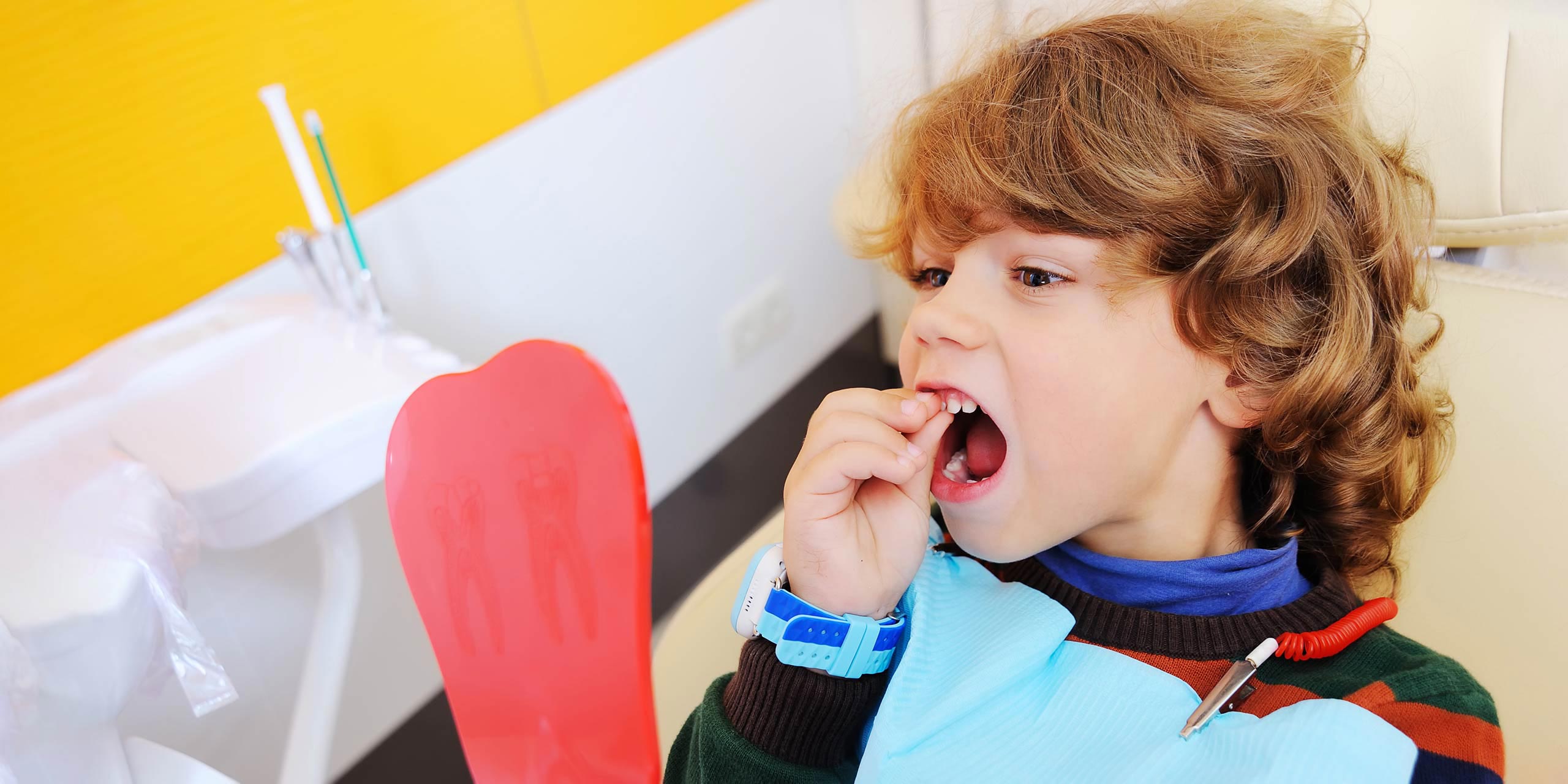 Kleiner Junge beim Zahnarzt zieht an seinem Zahn